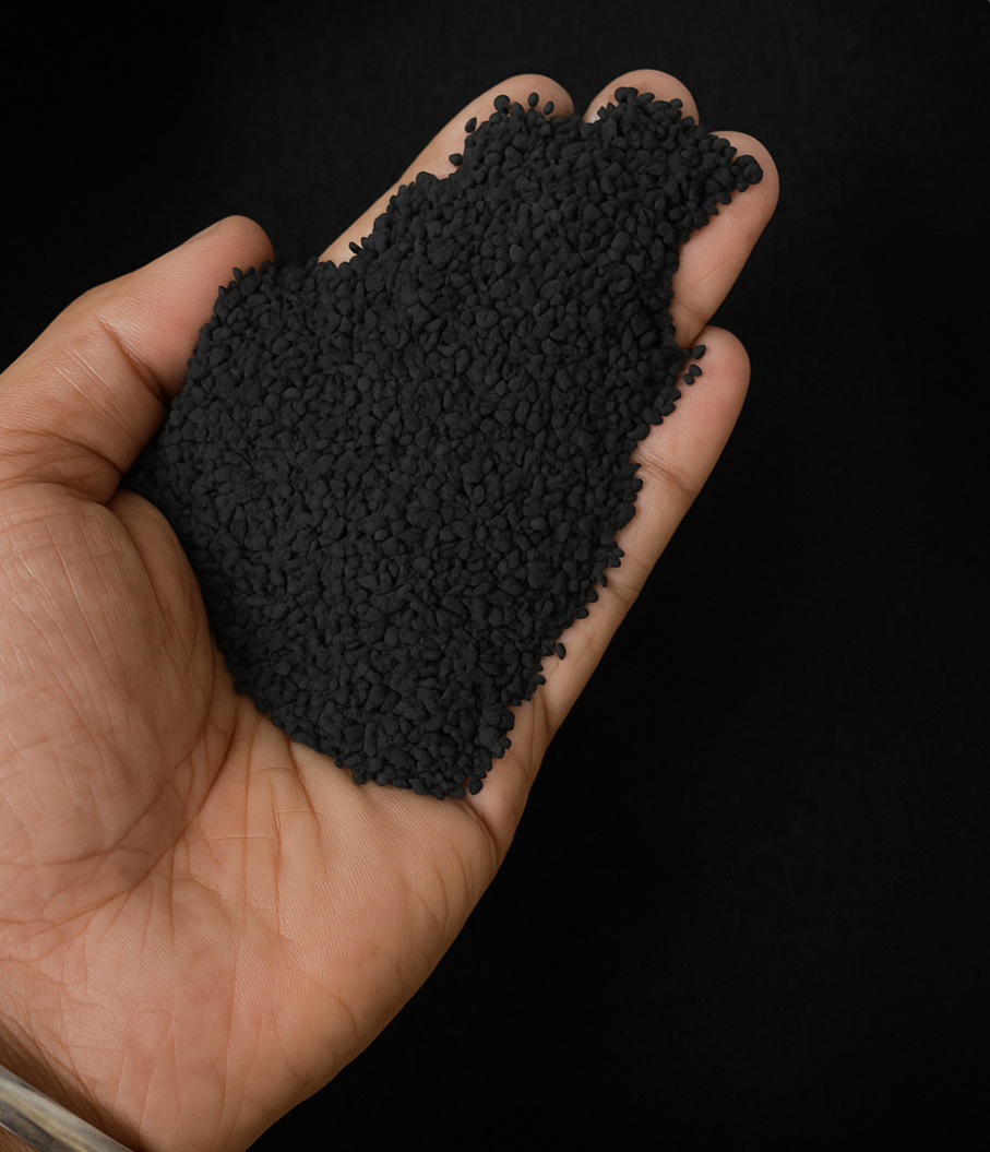 Hand holding a small amount of black powder against a dark background